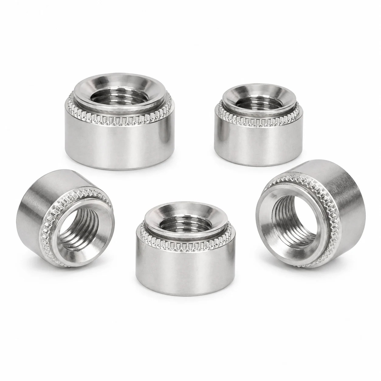 Five stainless steel round self clinching nuts in multiple sizes showing smooth cylindrical bodies top clinching rings and visible internal threads on a pure white background